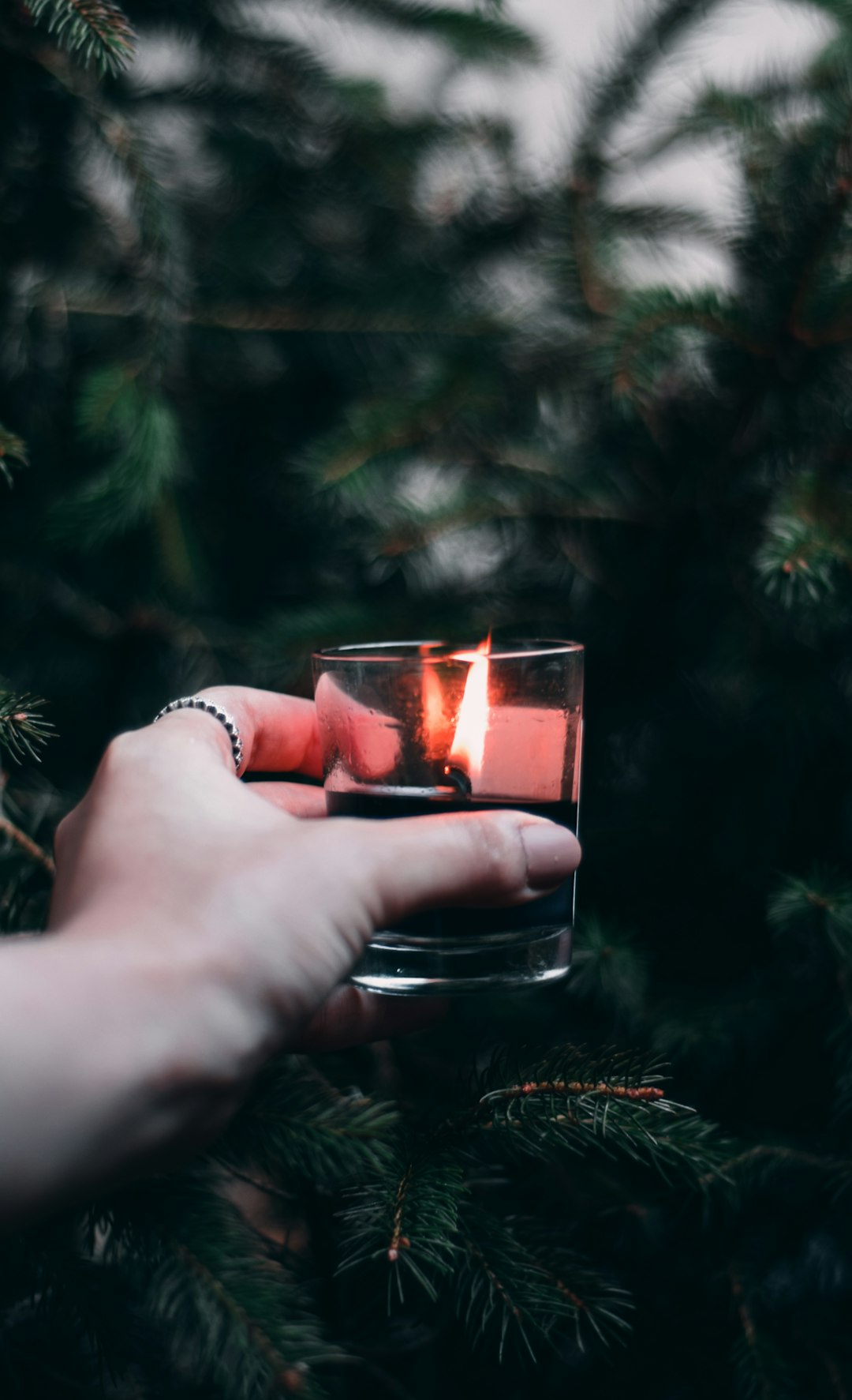 person holding clear glass candle holder