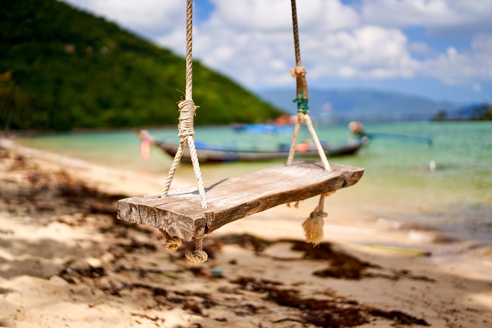 brown wooden swing on brown sand during daytime