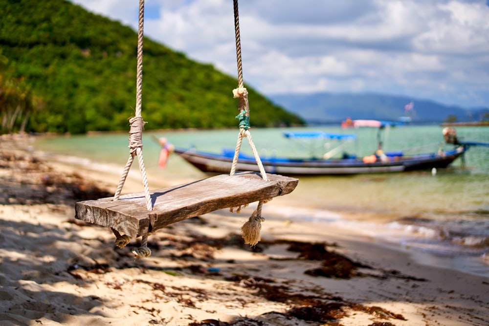 brown wooden swing on brown sand during daytime