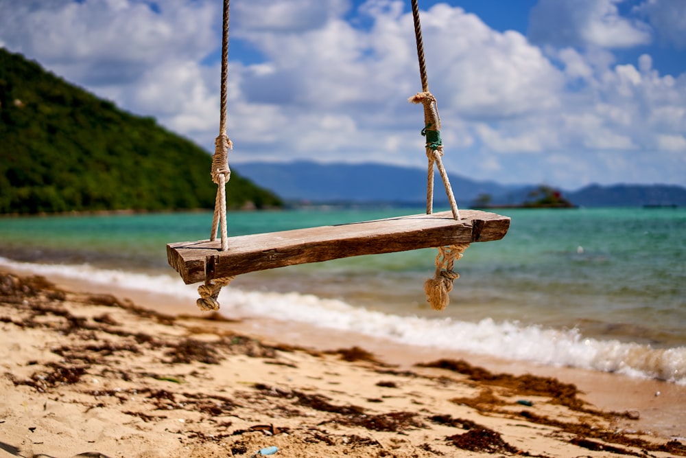 brown wooden swing on brown sand during daytime