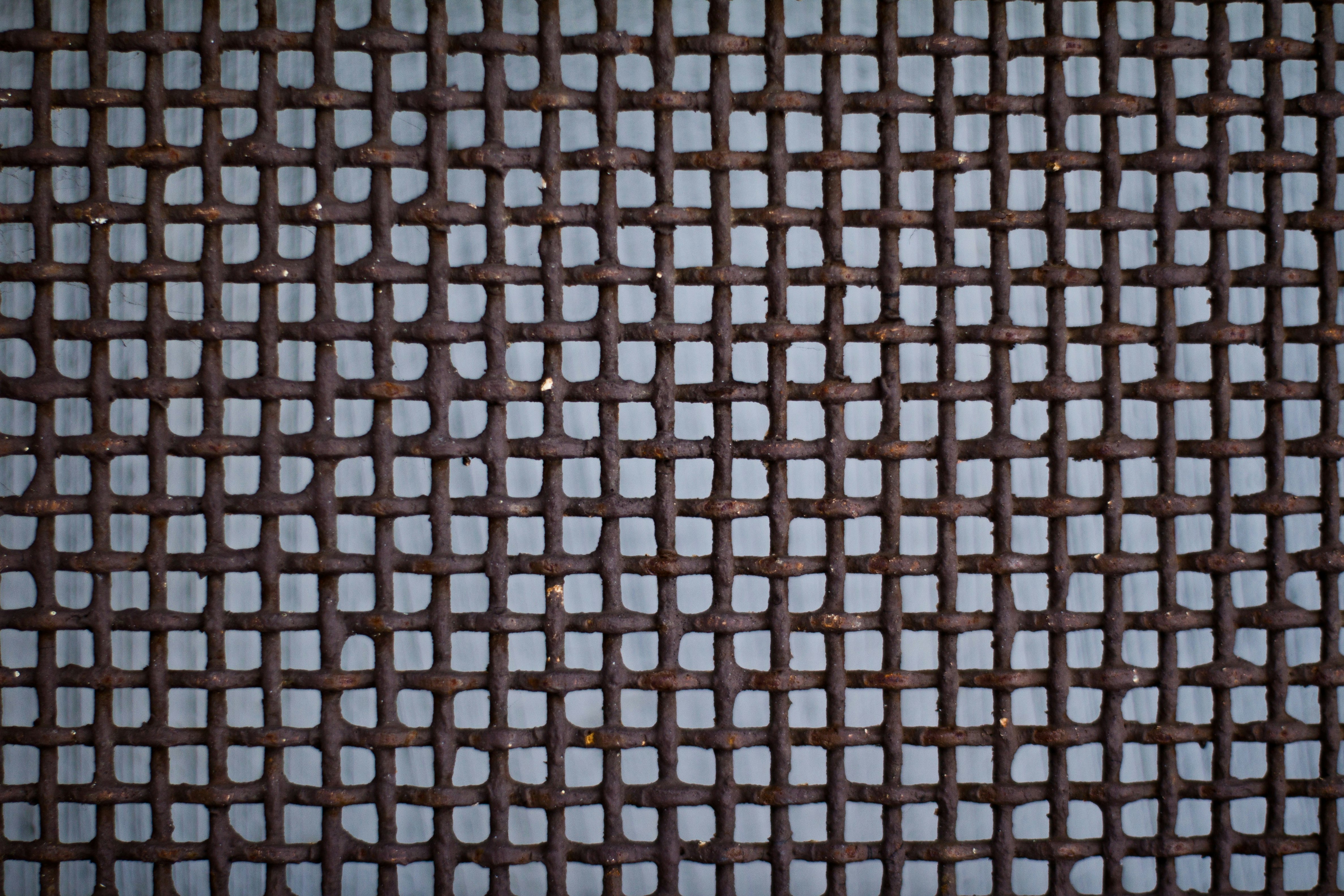 Arusted metal grate sits against a gray background.