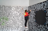 A painter finishing the last touches on a vibrant accent wall in a cozy bedroom.