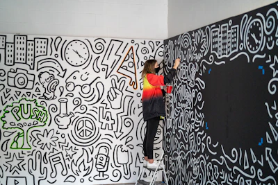 Skilled artist applying detailed paintwork on a large outdoor rockwall.