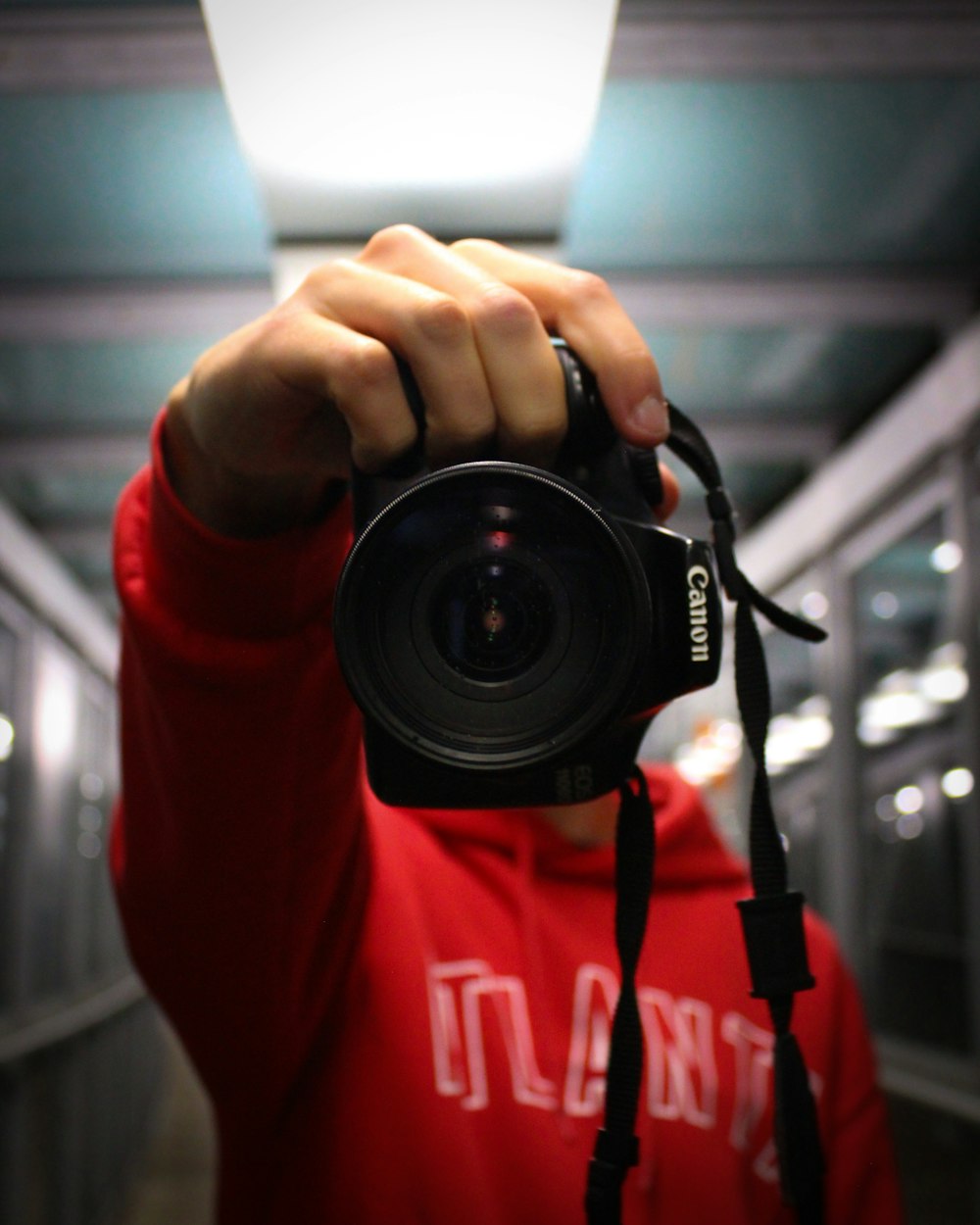 person in red long sleeve shirt holding black nikon dslr camera