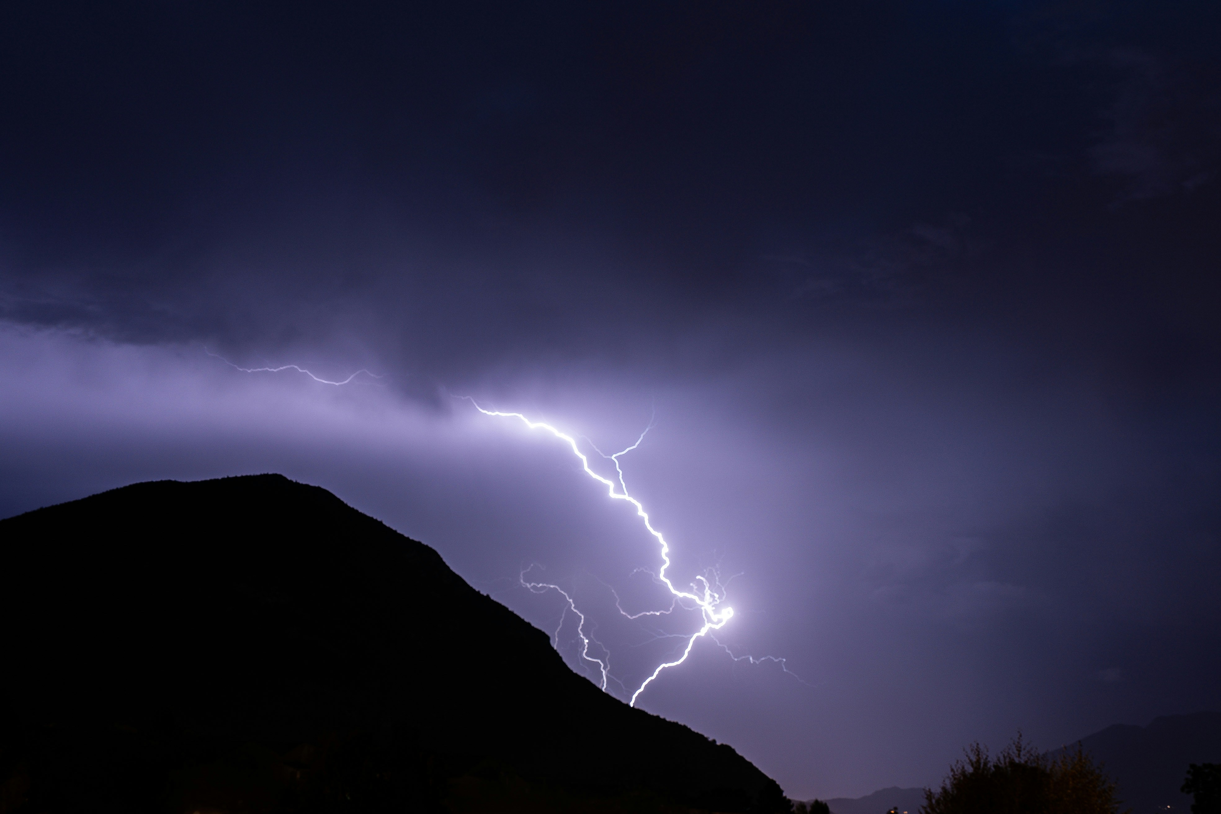 A lightning bolt hitting a mountain in the night sky photo – Free ...