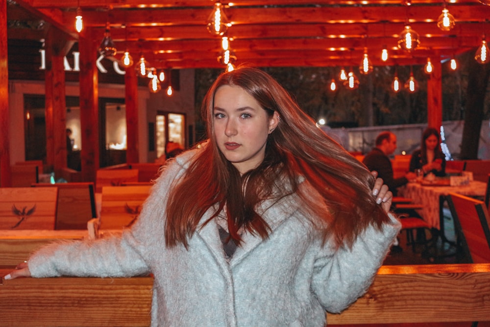 woman in gray sweater standing near brown wooden table