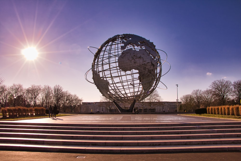 statua del globo in bianco e nero su panca di legno marrone durante la notte