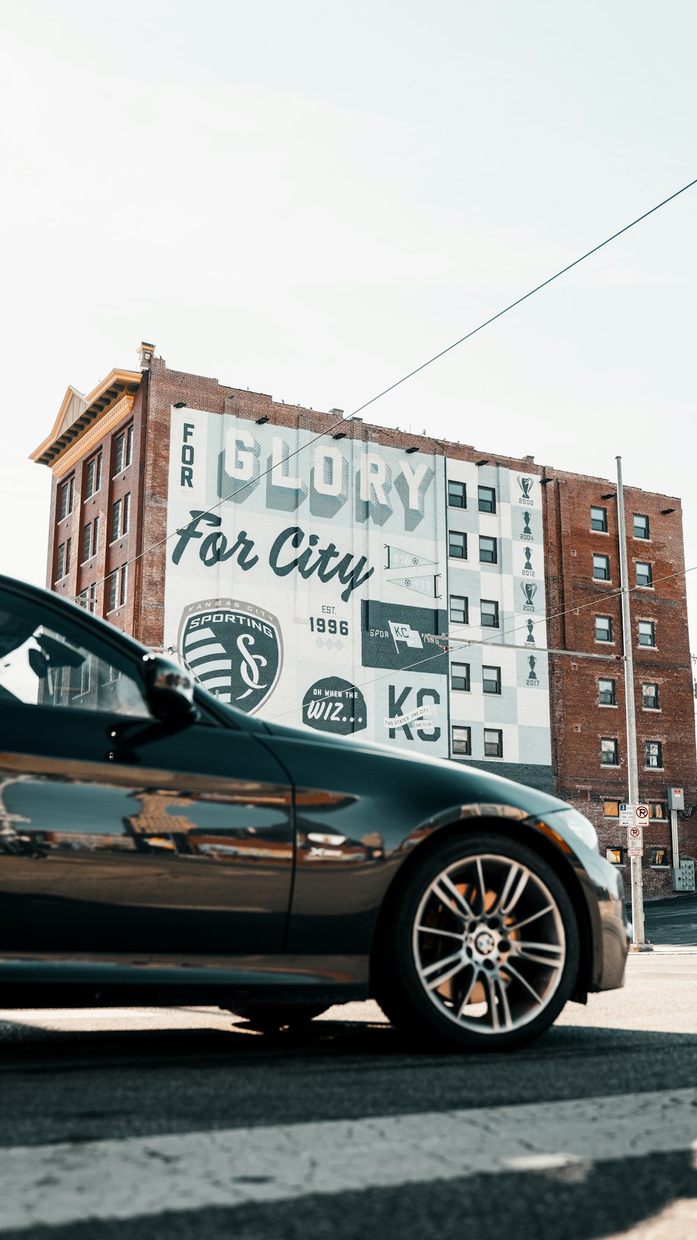 black car parked beside white and brown concrete building during daytime