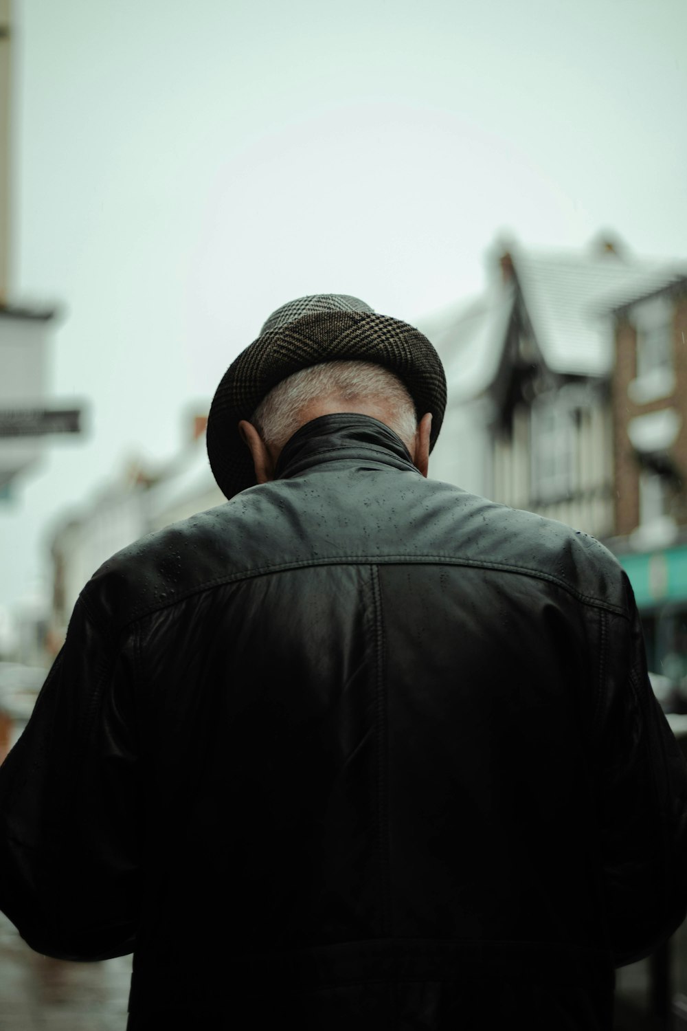 Homme en veste noire portant un chapeau fedora marron