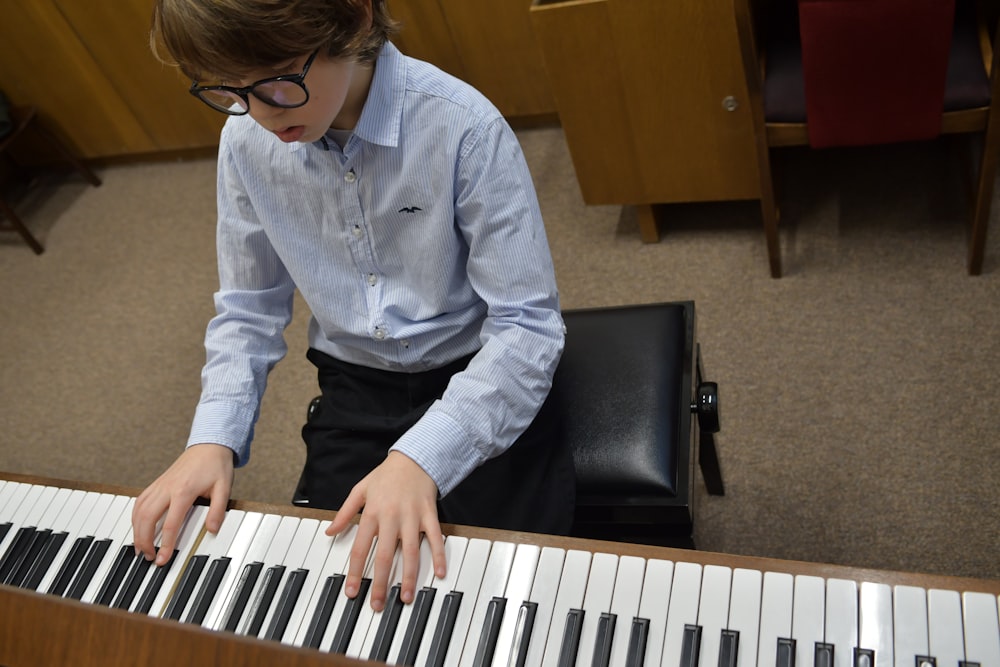 ragazzo in giacca di jeans blu che suona il pianoforte