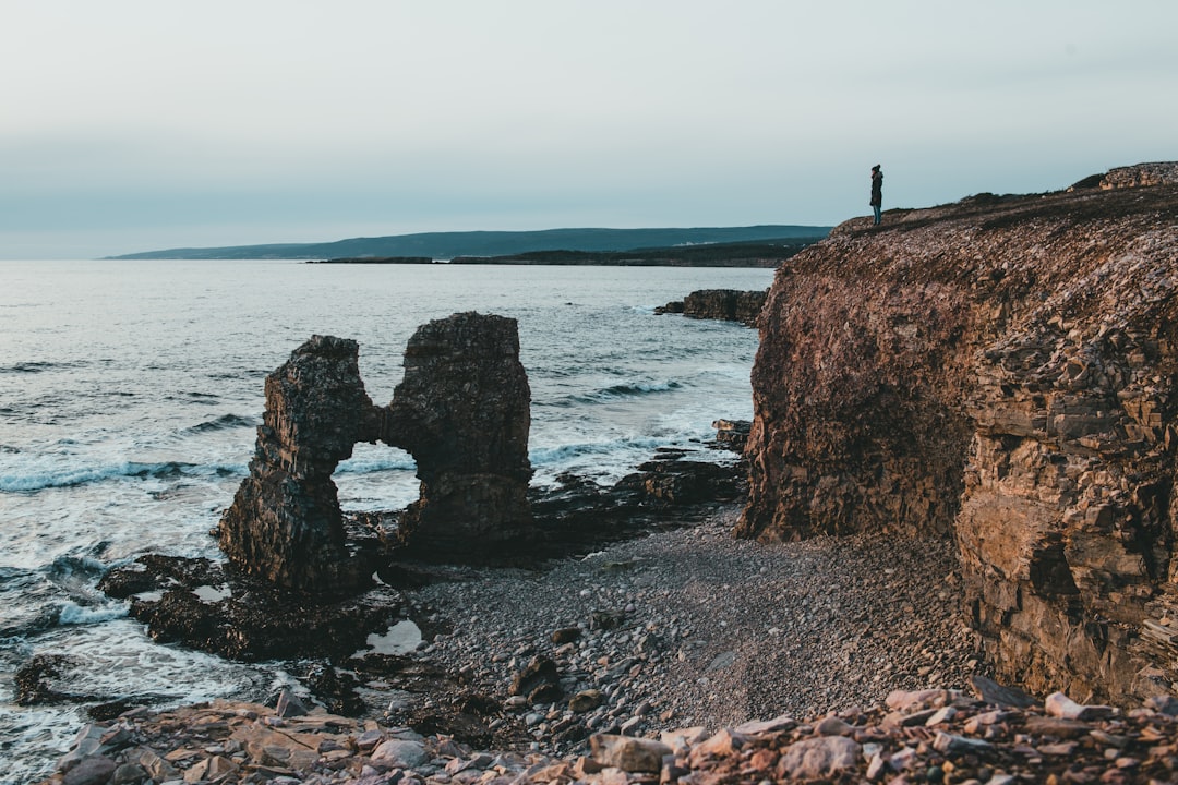 person standing on rock formation near sea during daytime