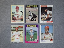 A collection of six vintage baseball cards featuring players from different teams, neatly arranged on a gray surface. Each card displays a portrait or action shot of a player, along with their team name and position.