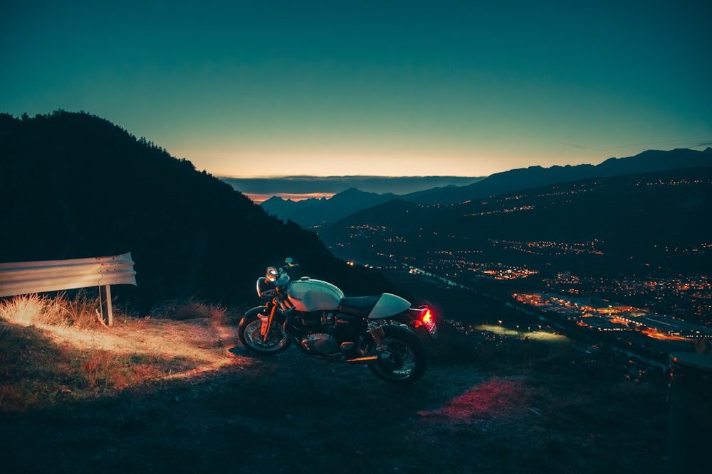 moto noire et rouge sur un chemin de terre brun pendant la journée