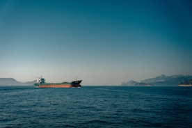 A cargo ship navigating through calm waters under blue skies.