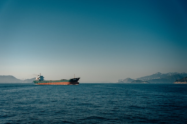A majestic cargo ship cutting through calm seas under a clear blue sky.