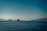 A cargo ship sailing smoothly across calm ocean waters under a clear sky.