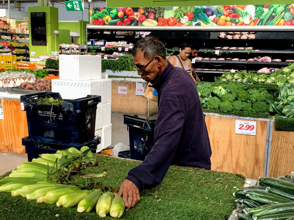 man in black jacket holding green vegetable