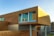 A modern architectural building featuring a design with horizontal wooden panels and large windows reflecting the sky. The structure appears elevated with visible support columns underneath, showcasing a blend of contemporary materials and finishes.