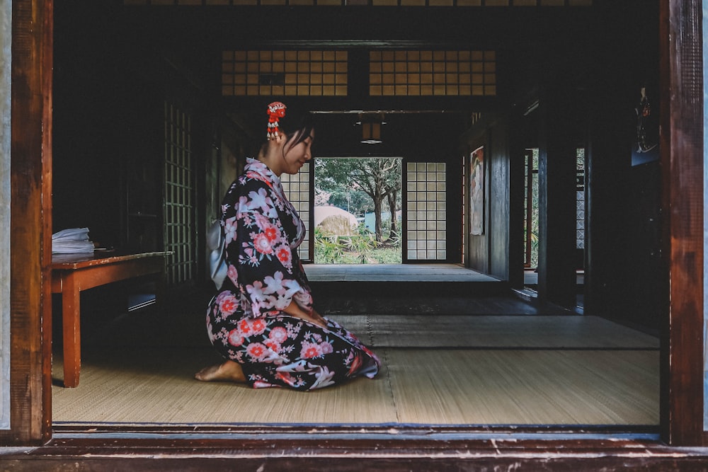 woman in black red and white floral dress sitting on brown wooden floor