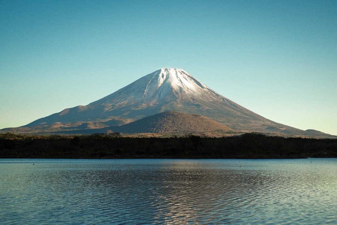 mountain range near body of water under blue sky during daytime