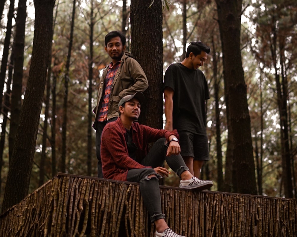 man in red jacket sitting on brown tree log