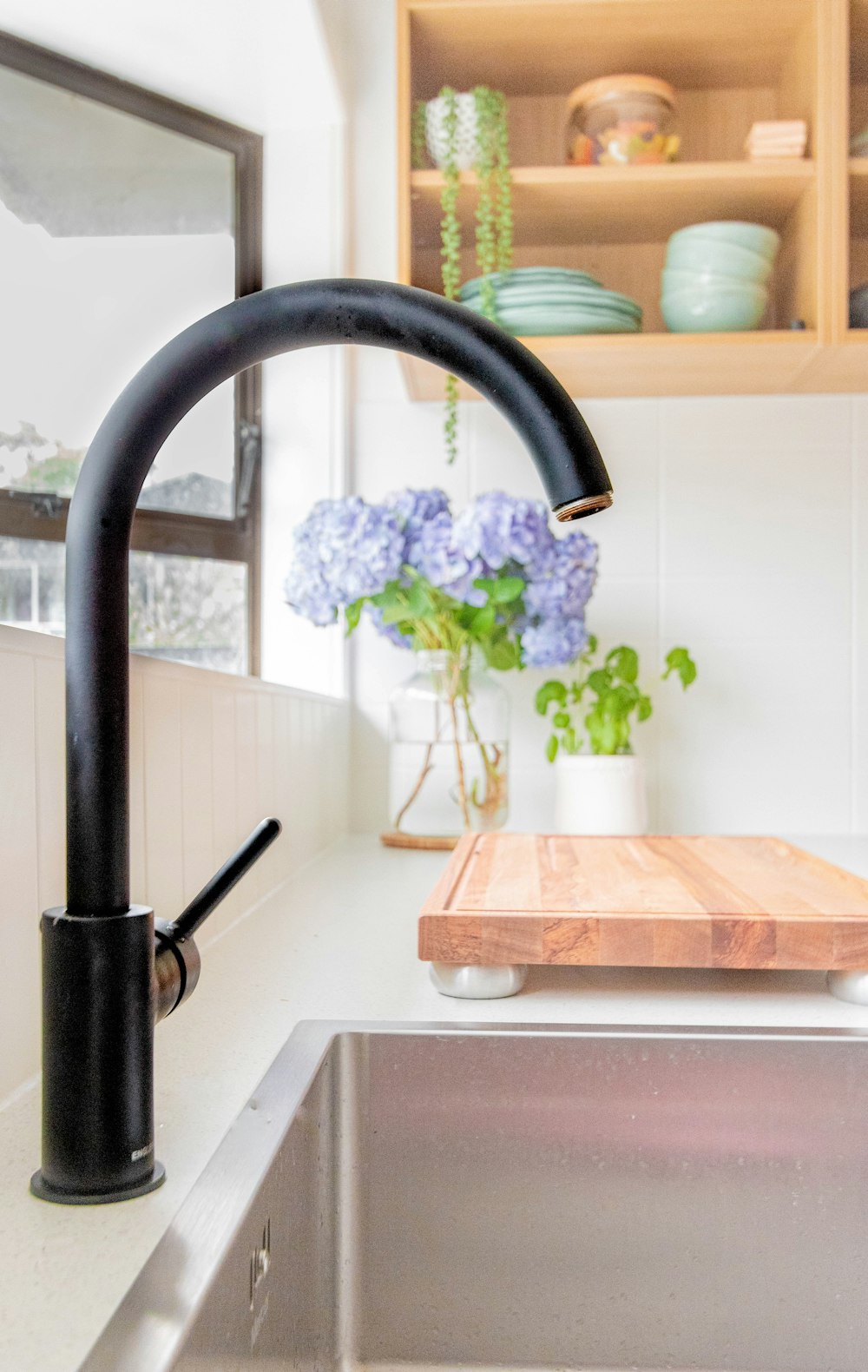 black metal faucet near brown wooden chopping board