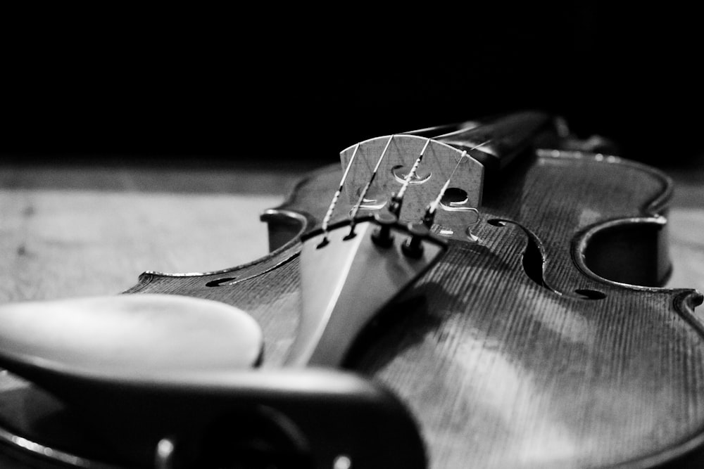 grayscale photo of violin on wooden surface