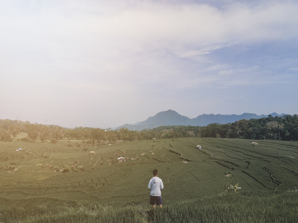 man in white shirt standing on green grass field during daytime