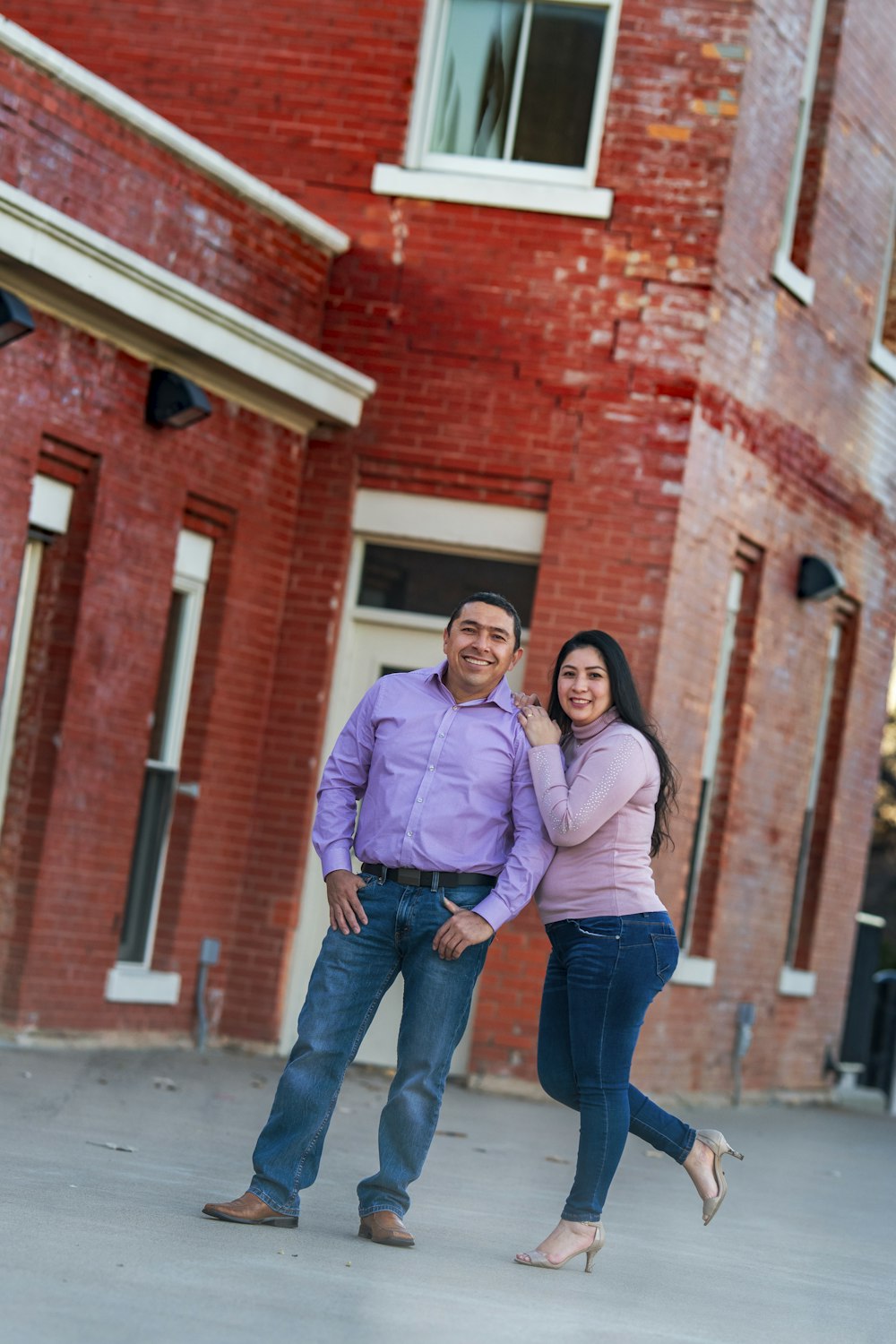 couple standing beside brown brick building during daytime