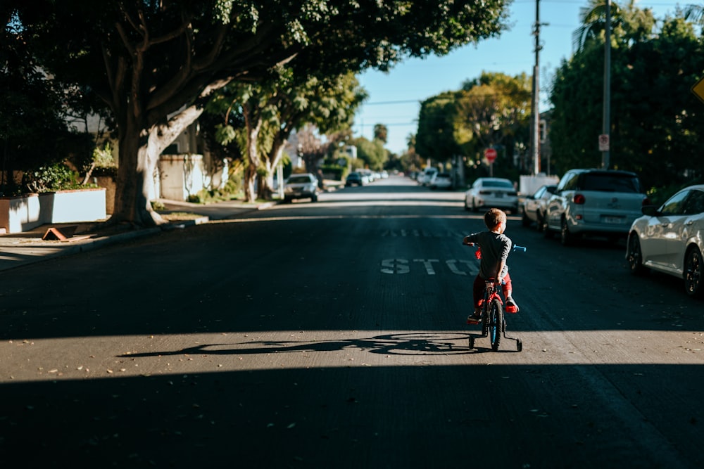 man in red shirt riding bicycle on road during daytime