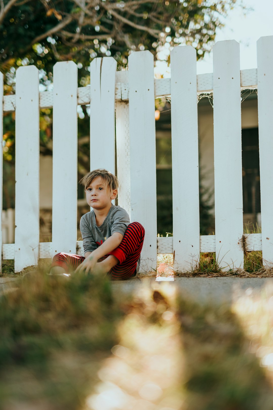 girl in red and white striped long sleeve shirt sitting on grass field