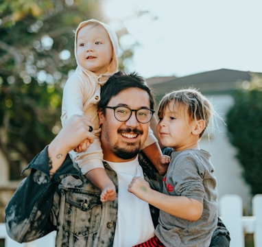 man in white shirt carrying girl in gray shirt