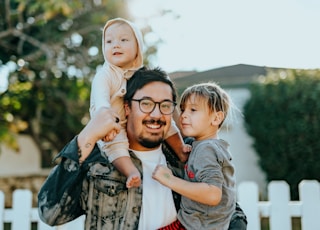 man in white shirt carrying girl in gray shirt