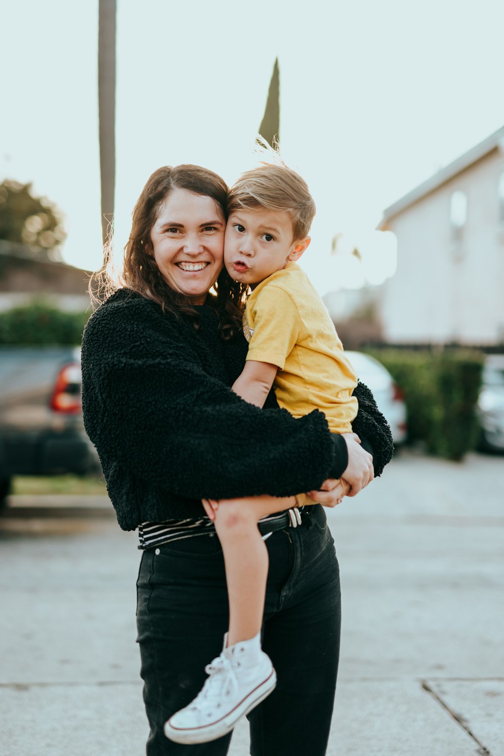 woman in black sweater carrying girl in yellow jacket