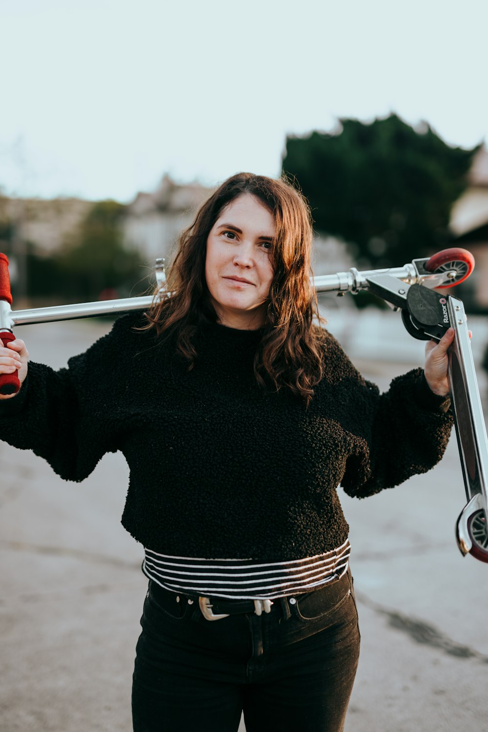 woman in black sweater and striped skirt holding a bicycle handle bar
