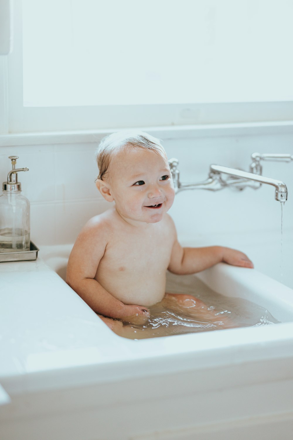 Oben-ohne-Baby auf weißer Badewanne