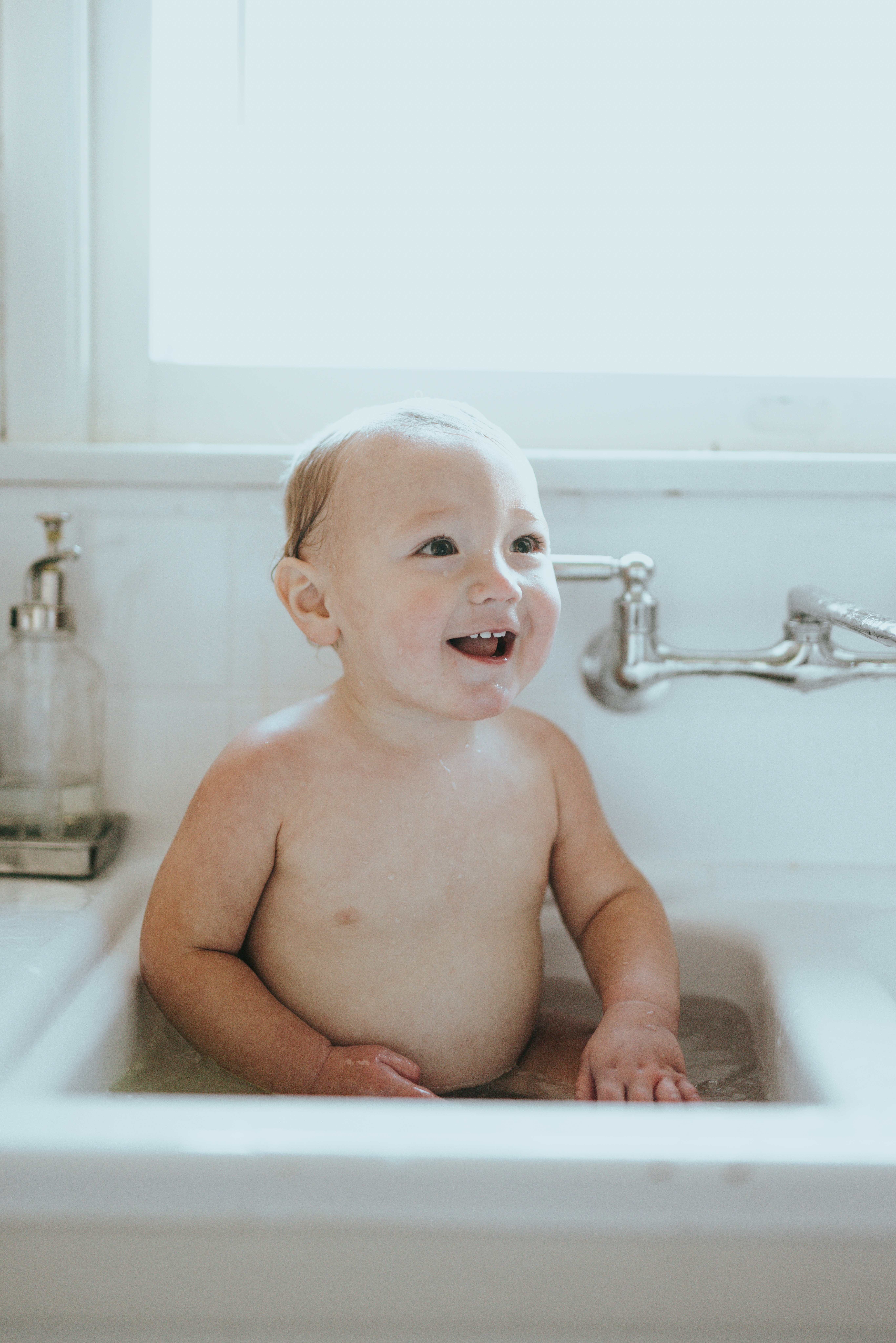 topless baby lying on white ceramic bathtub