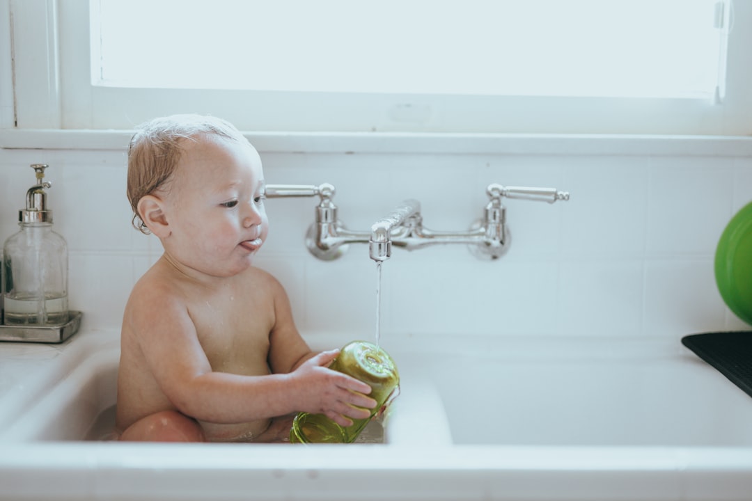 topless baby holding green apple in bathtub