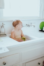 topless child sitting on bathtub
