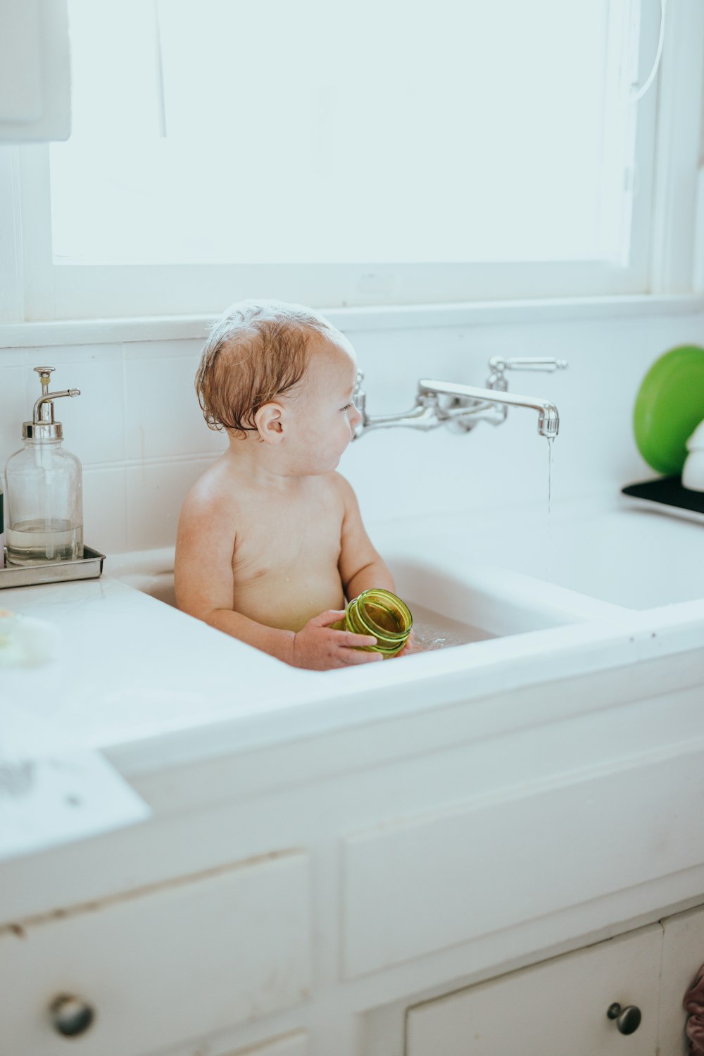topless child sitting on bathtub