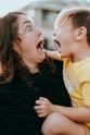 woman in black sweater kissing girl in yellow shirt