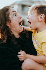 woman in black sweater kissing girl in yellow shirt