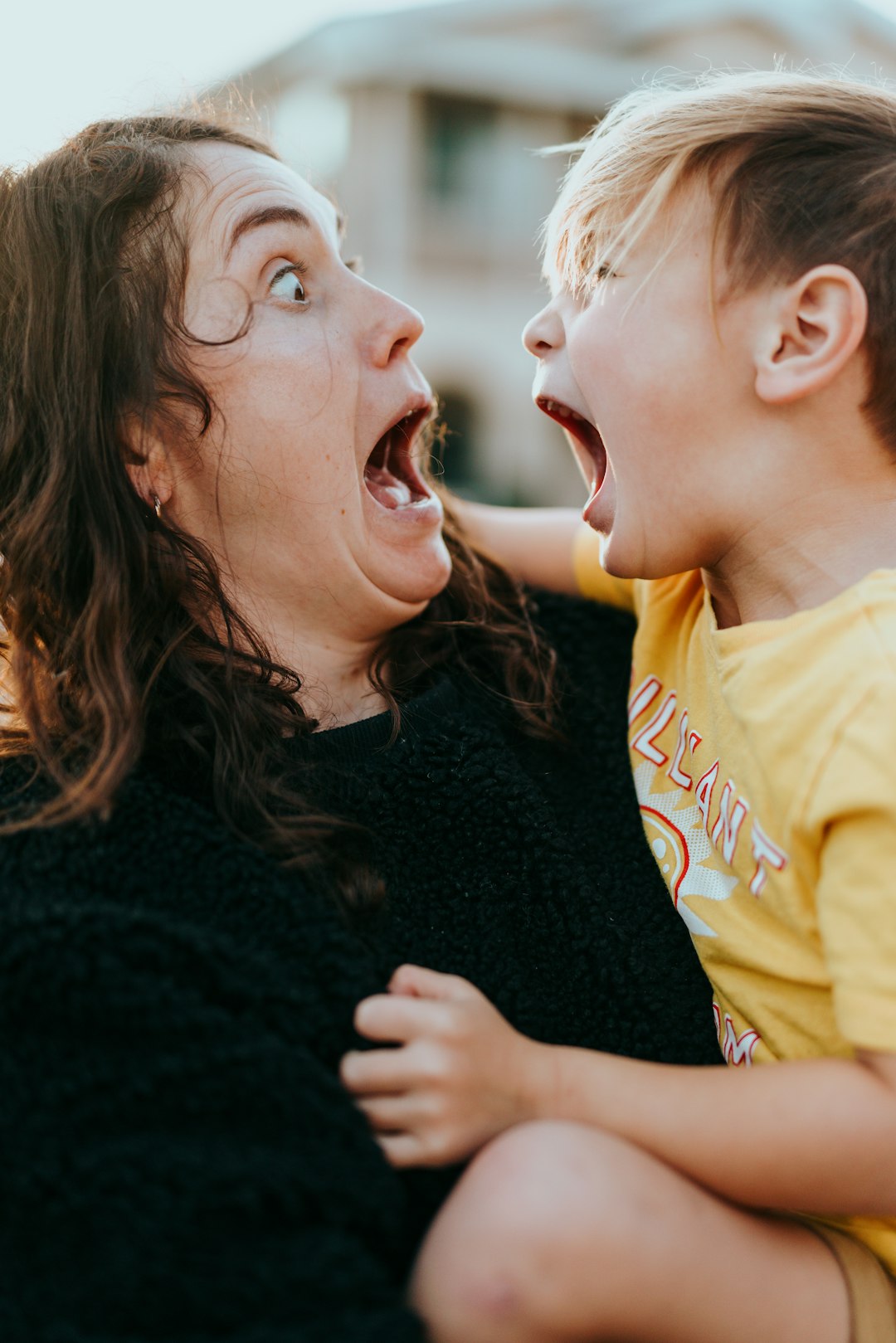 woman in black sweater kissing girl in yellow shirt