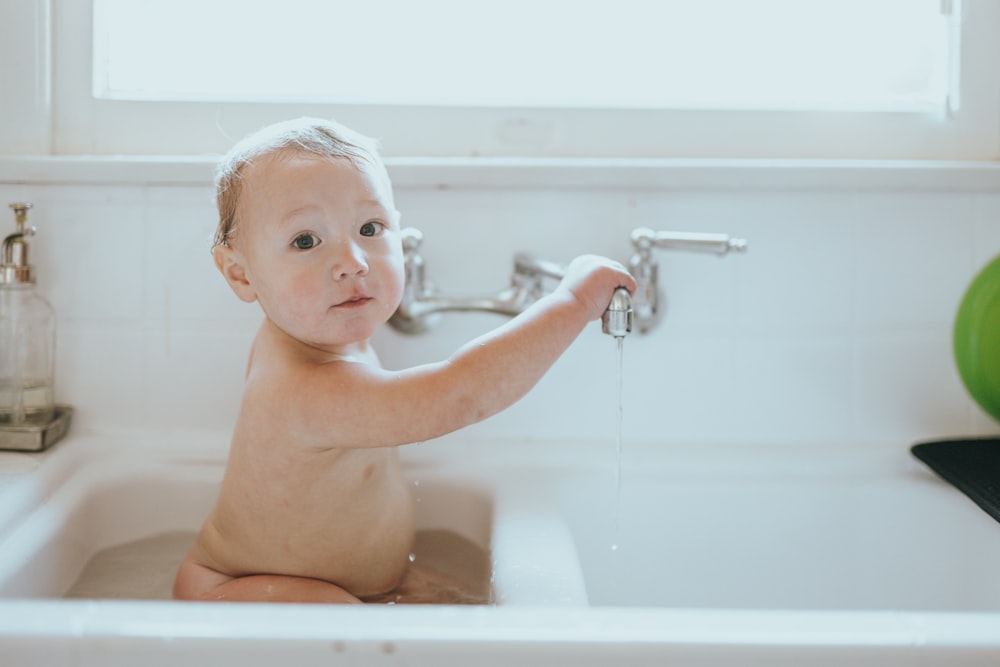 topless baby in bathtub with water