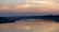 A serene river at sunset with gentle ripples reflecting the warm colors of the sky, symbolizing the river mouth.