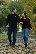 Novios caminando de la mano en un parque, sonriendo y disfrutando su historia juntos.