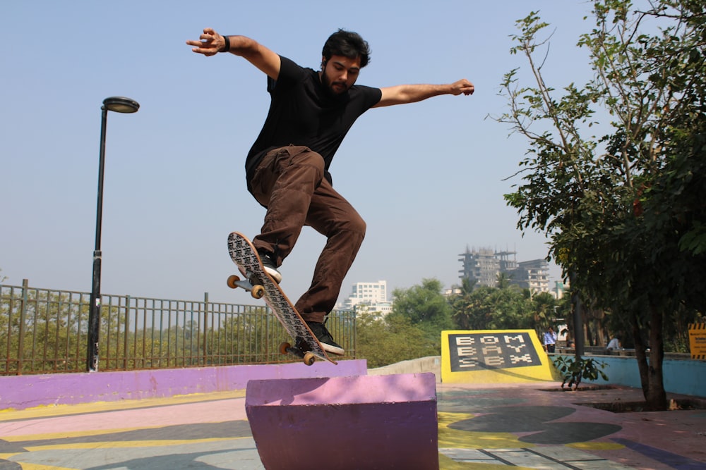 man in black t-shirt and brown pants riding skateboard during daytime