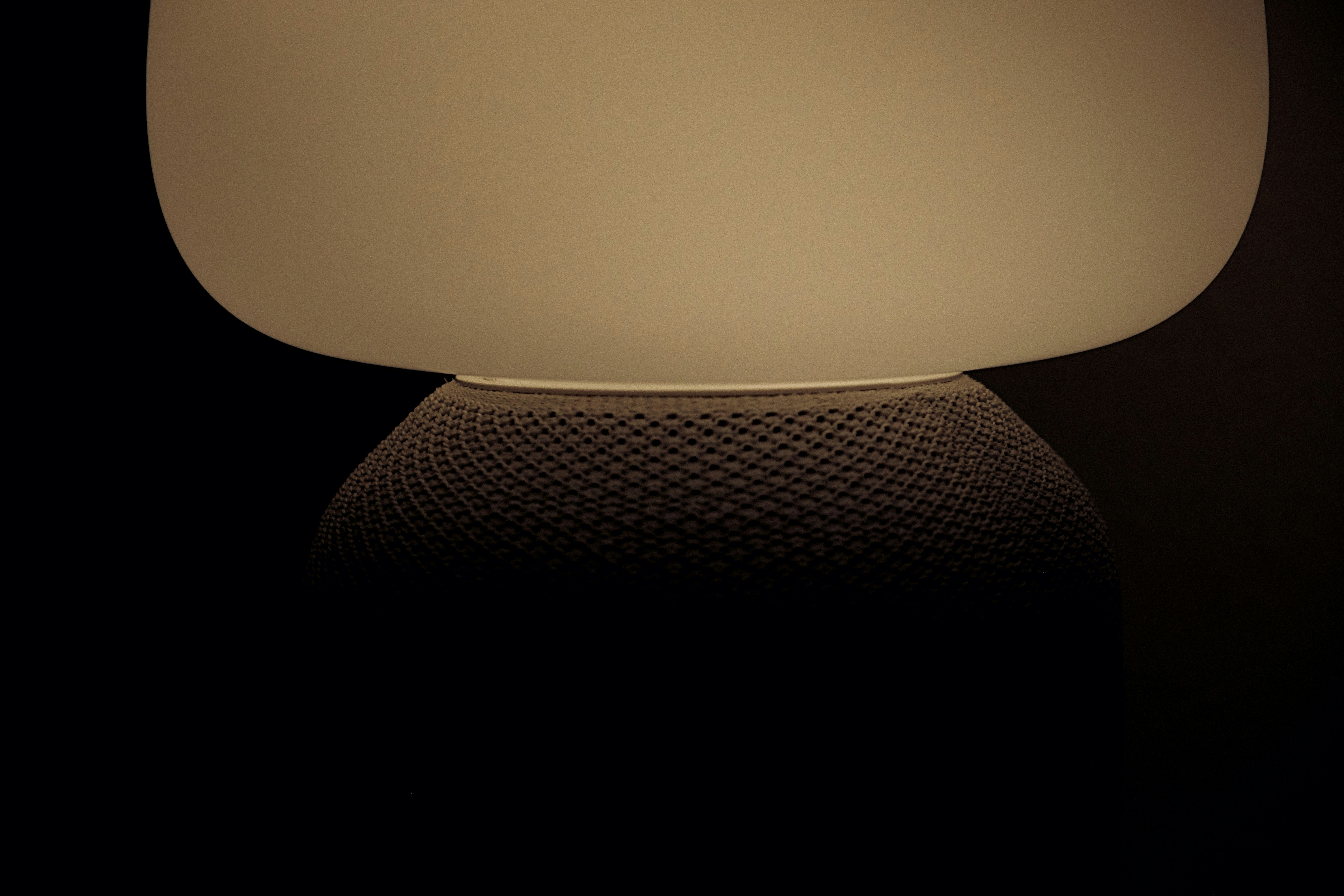 Close-up of a cylindrical PVC pipe Bluetooth speaker with speaker grille showing warm orange ambient glow — similar to Turnup Speakers design