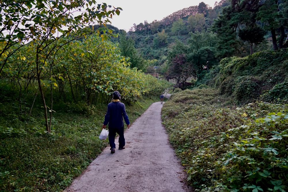 uomo in giacca blu che cammina sul sentiero durante il giorno