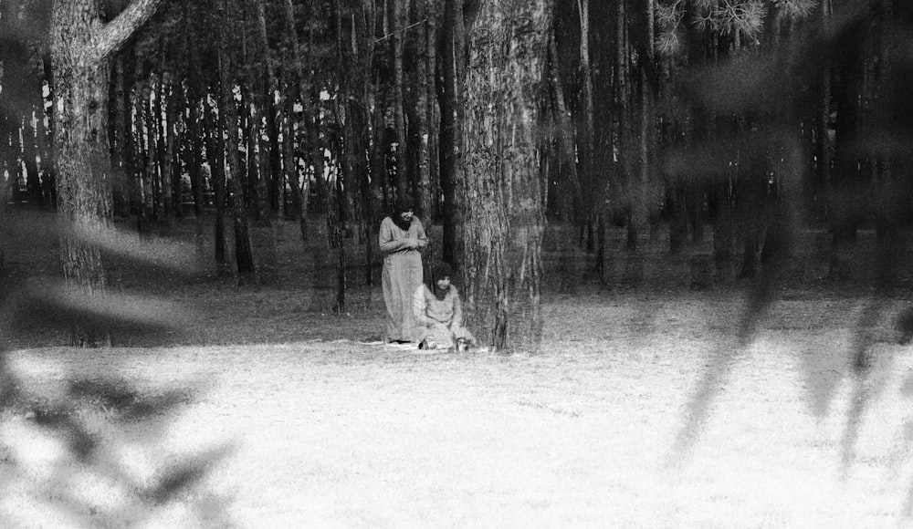 grayscale photo of man and woman walking on snow covered ground